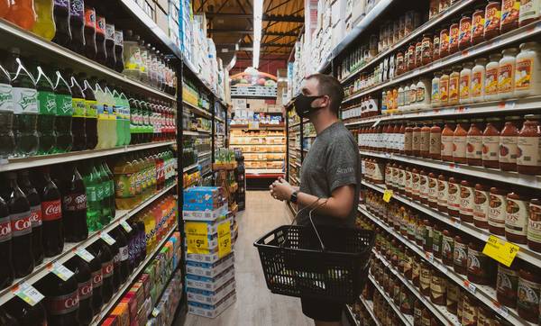 Canadian shopper using grocery coupons at checkout in a supermarket