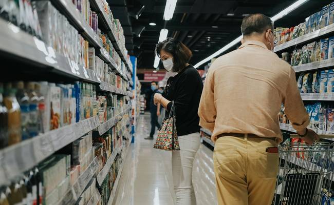 Shoppers comparing printed coupons at a Canadian grocery aisle