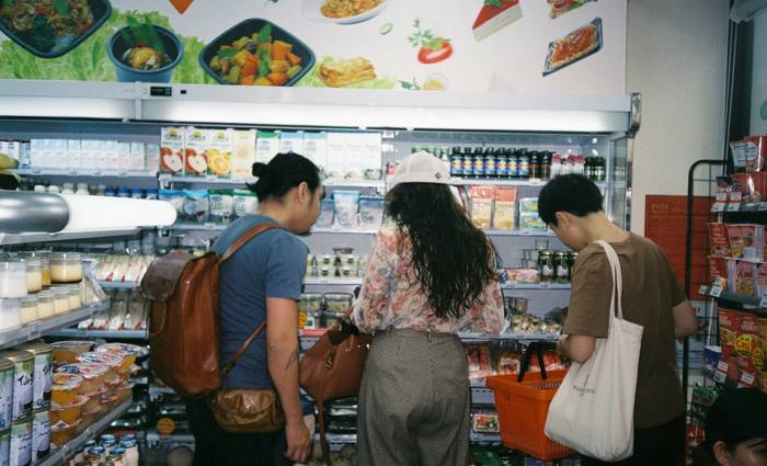 Canadian family comparing grocery savings apps on their phone in a supermarket aisle