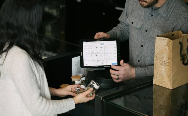 Canadian Tire cashier scanning a Triangle Rewards app while customer hands over paper coupon