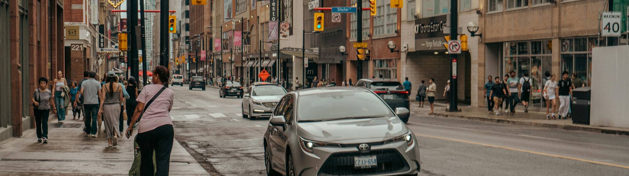 Canadian traveller holding car keys beside a rental car in downtown Toronto
