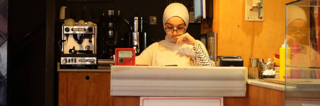Color photograph of a person checking loyalty points balance on a mobile phone in a Canadian café