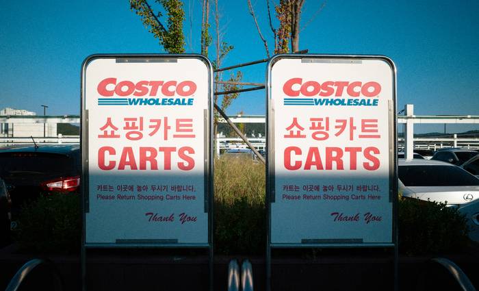 Canadian Costco warehouse entrance with shoppers and carts, illustrating coupon policy context