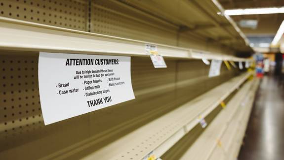Costco coupon booklet and instant savings signage on warehouse shelf in Canada