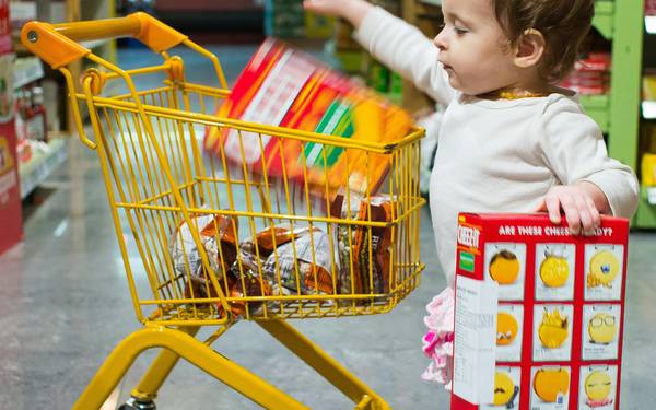 Canadian family learning to use coupons while shopping for groceries in a supermarket