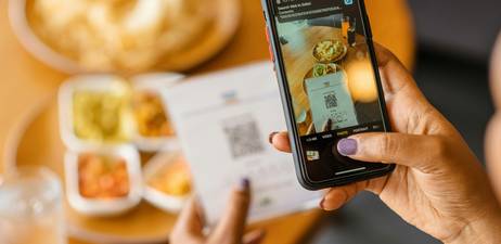 Comparison of digital grocery coupon app open on phone and printed coupons on a Canadian kitchen counter