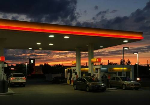 Person filling a car at dusk, timing fuel purchase for lower prices