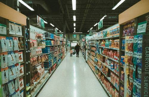 Canadian shoppers comparing grocery savings apps on a phone in a Canadian supermarket