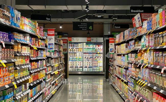 Canadian shopper using grocery coupons and phone app in supermarket aisle