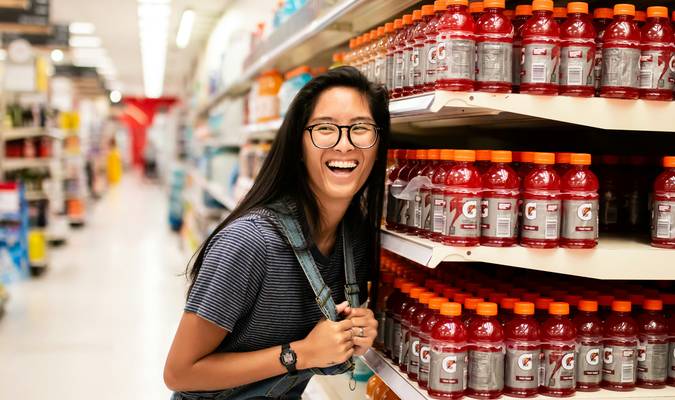 Smiling Canadian shopper redeeming grocery coupons at supermarket checkout