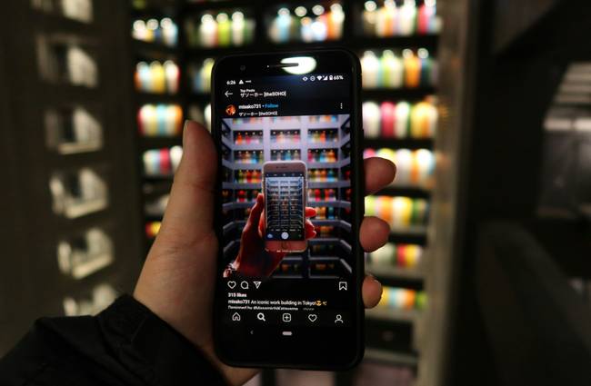 Canadian shopper in grocery store aisle comparing digital flyers on their smartphone for best deals