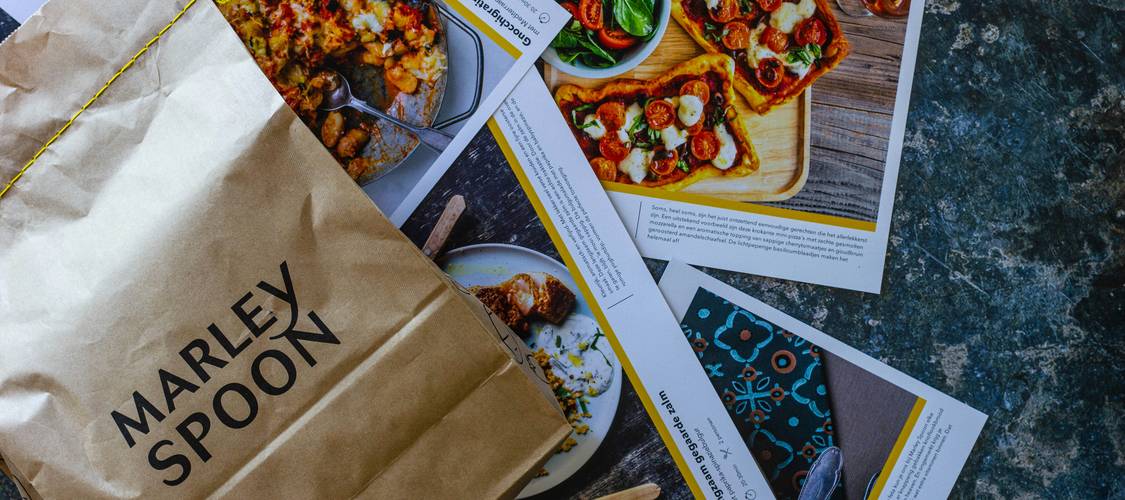 Canadian shoppers comparing weekly grocery flyers at a kitchen table for best deals