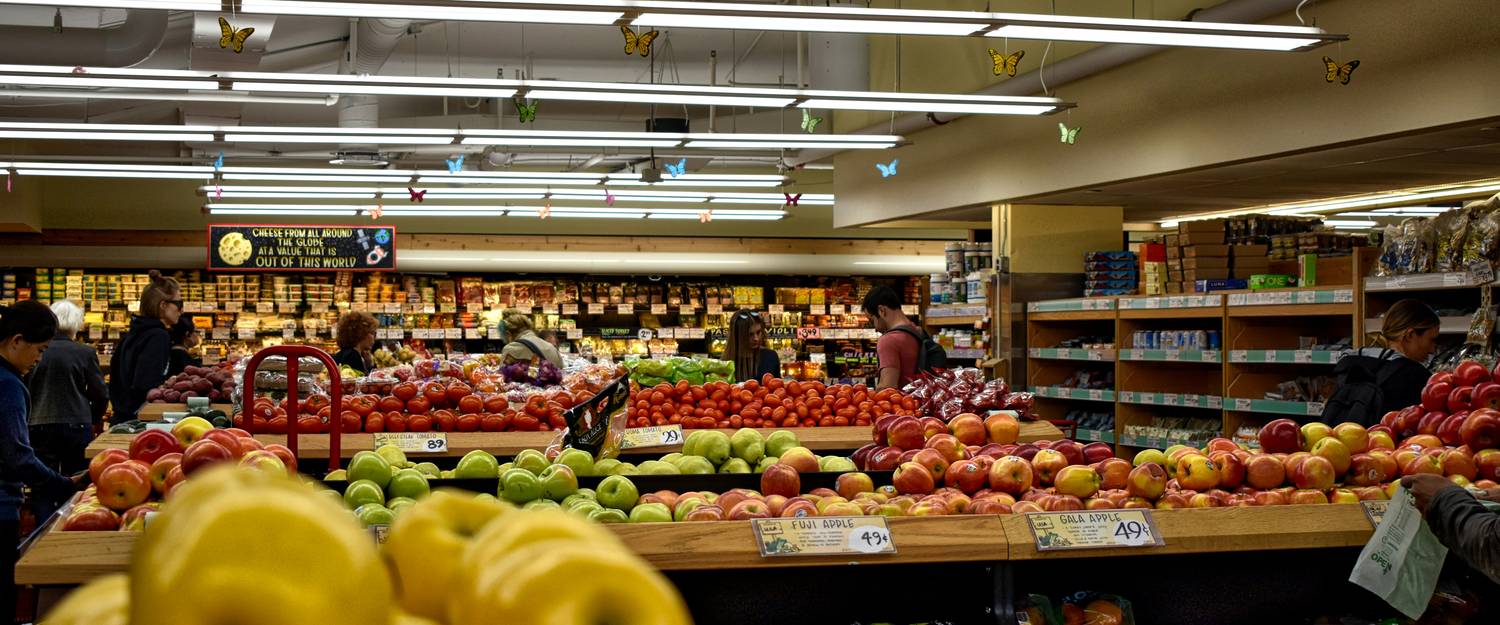 Canadian family shopping for groceries with coupons and rewards in a supermarket