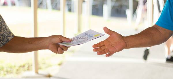 Canadian shopper handing a printed coupon to a cashier at a grocery store