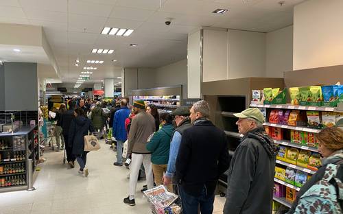 Canadian shopper redeeming paper and digital grocery coupons at supermarket checkout