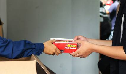 Hands holding manufacturer coupons and showing PC Optimum app at Canadian grocery checkout