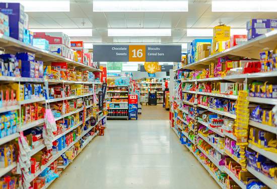 Walmart shoppers using digital and printable coupons in a Canadian supermarket aisle for 2025 grocery savings