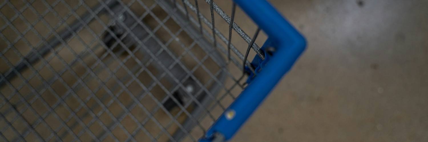 Canadian shopper pushing a cart while holding printed coupons inside Walmart