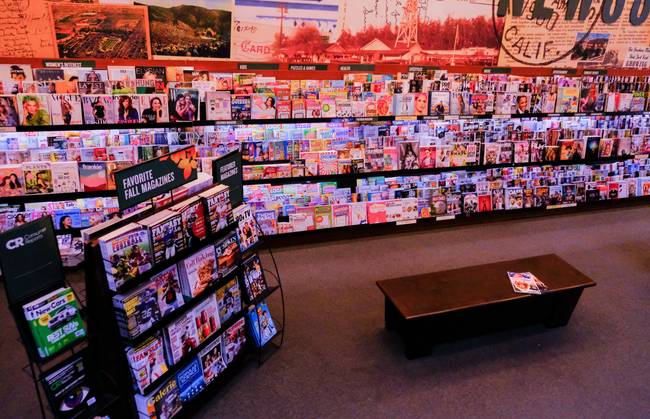Canadian shopper reviewing weekly flyers and coupons in a grocery store aisle for savings