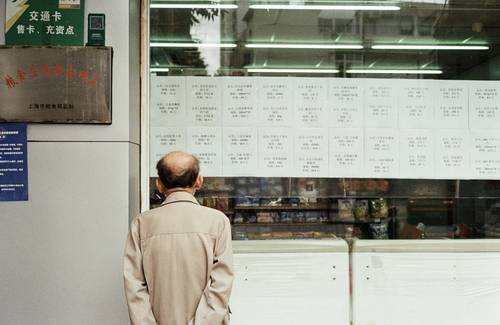 Cashier reviewing a competitor's flyer for price matching in a Canadian store